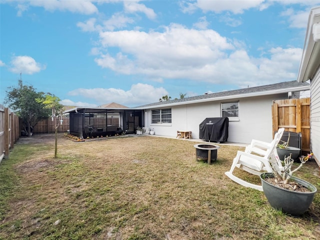 rear view of property with a yard and a fire pit