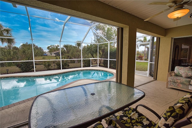 view of swimming pool featuring ceiling fan, a lanai, and a patio