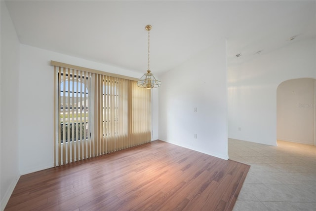 unfurnished dining area featuring vaulted ceiling and light hardwood / wood-style flooring