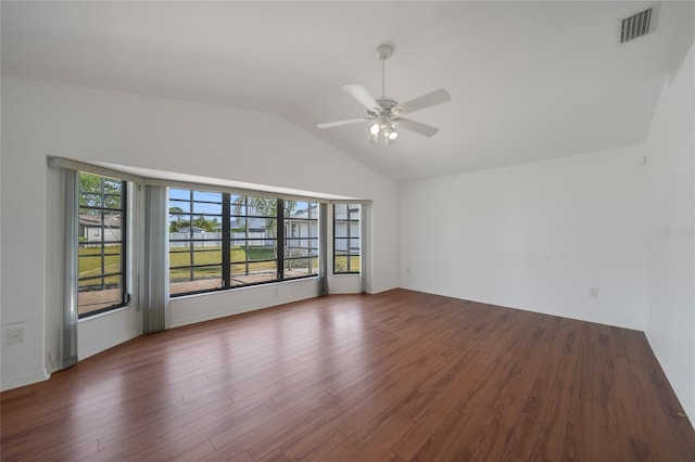 empty room with dark wood-type flooring, vaulted ceiling, and a wealth of natural light