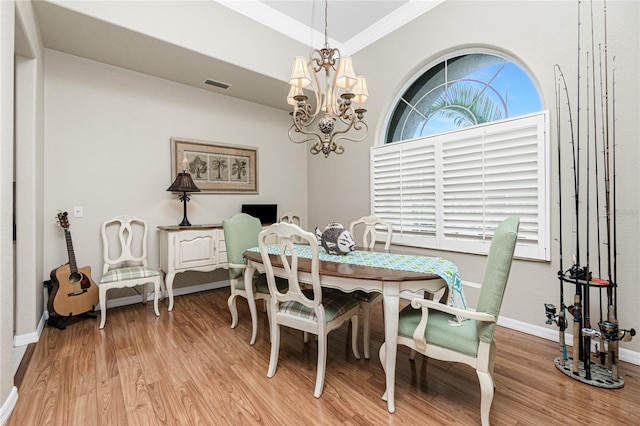 dining area featuring wood-type flooring, ornamental molding, and a chandelier