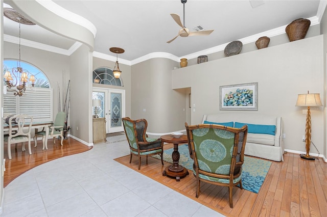 living room featuring french doors, ornamental molding, ceiling fan with notable chandelier, and light hardwood / wood-style flooring