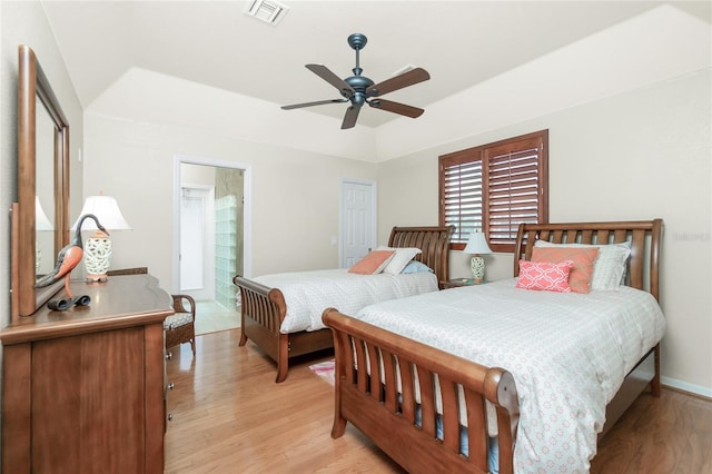 bedroom with ceiling fan, a raised ceiling, and light hardwood / wood-style flooring