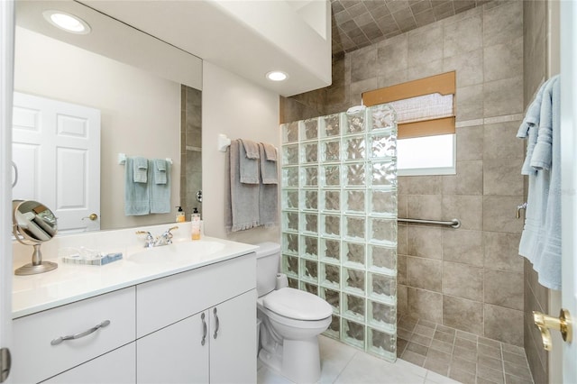 bathroom featuring vanity, tiled shower, tile patterned floors, and toilet