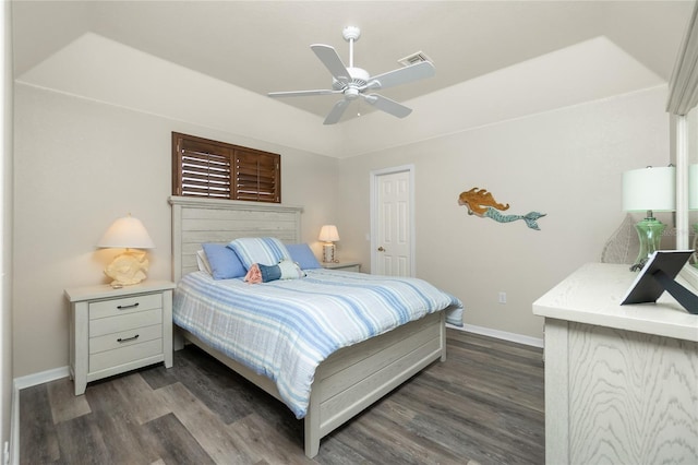 bedroom with dark wood-type flooring, ceiling fan, and a raised ceiling