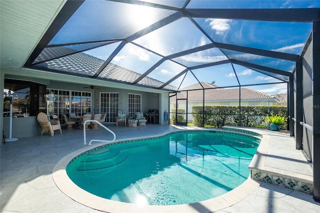 view of swimming pool featuring ceiling fan, a lanai, and a patio area