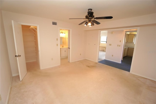 unfurnished bedroom with a walk in closet, light carpet, ensuite bath, and a closet