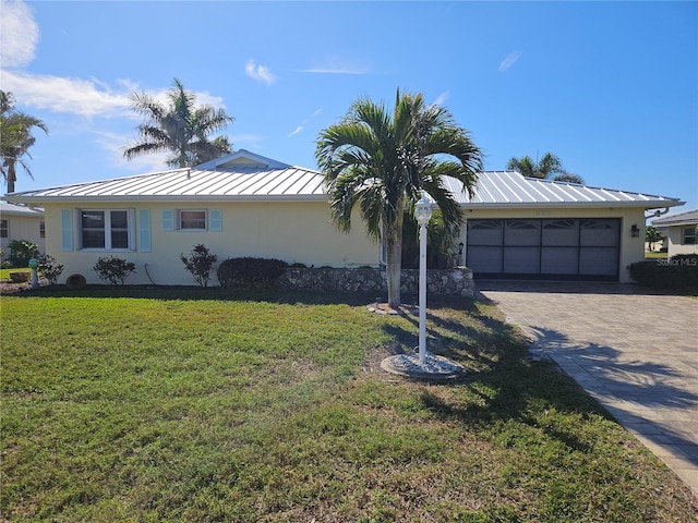 single story home featuring metal roof, decorative driveway, stucco siding, a standing seam roof, and a front yard