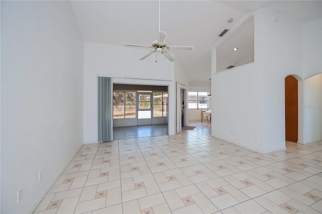 empty room featuring light tile patterned floors, a towering ceiling, and ceiling fan