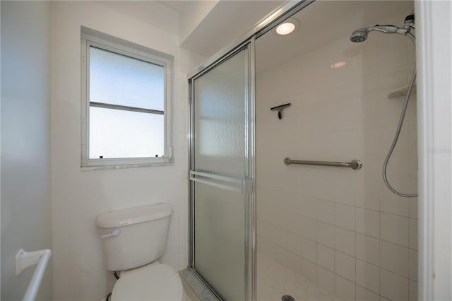 bathroom featuring toilet and a shower with door