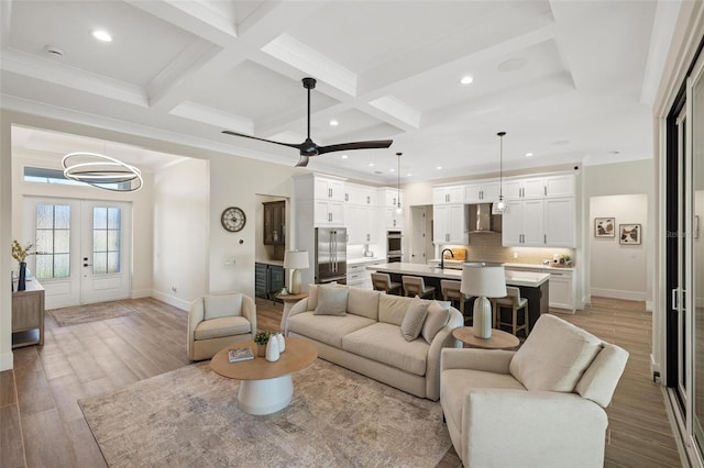 living room featuring beamed ceiling, coffered ceiling, french doors, and light hardwood / wood-style flooring