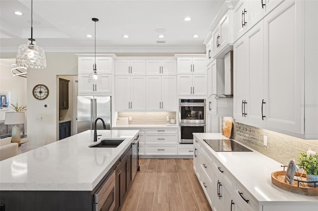 kitchen featuring pendant lighting, white cabinetry, built in appliances, and a kitchen island with sink