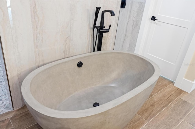 room details with hardwood / wood-style flooring and a bathing tub