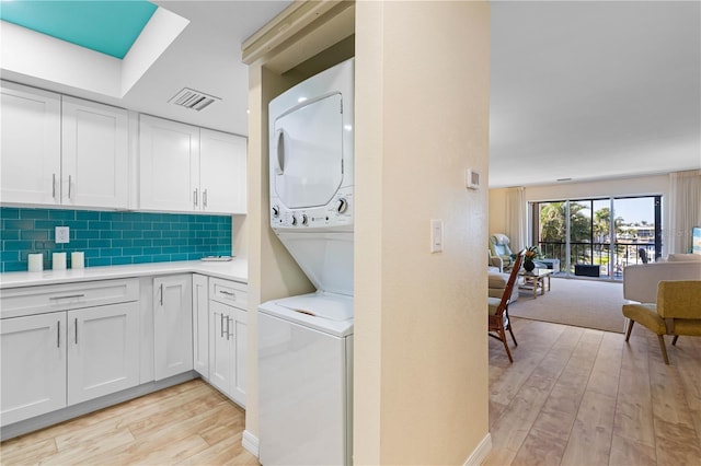 washroom featuring stacked washing maching and dryer and light hardwood / wood-style floors