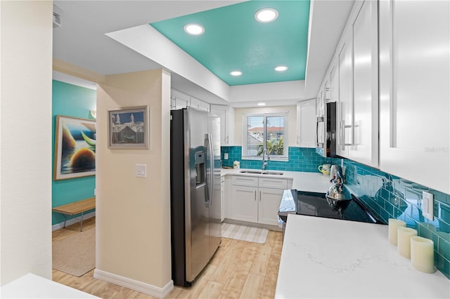 kitchen featuring light wood-type flooring, appliances with stainless steel finishes, sink, and white cabinets