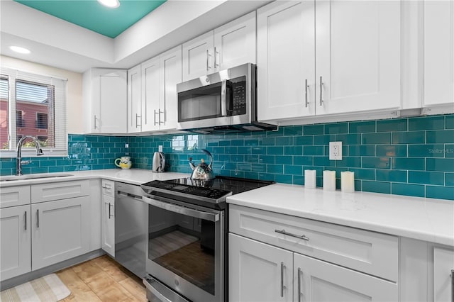 kitchen featuring appliances with stainless steel finishes, white cabinetry, sink, backsplash, and light hardwood / wood-style floors