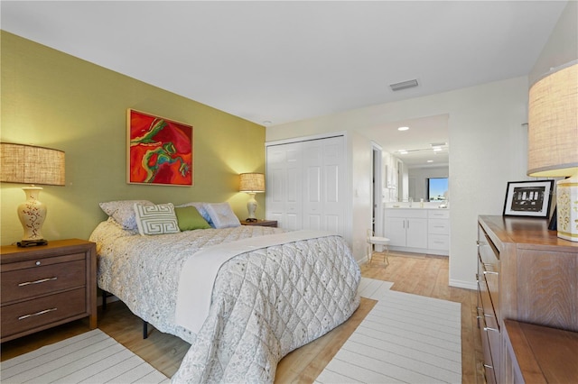 bedroom with a closet, ensuite bath, and light hardwood / wood-style flooring