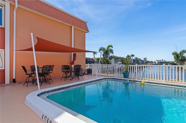 view of pool with a patio and a water view