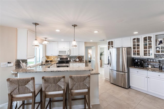 kitchen with white cabinetry, stainless steel appliances, light stone countertops, and sink