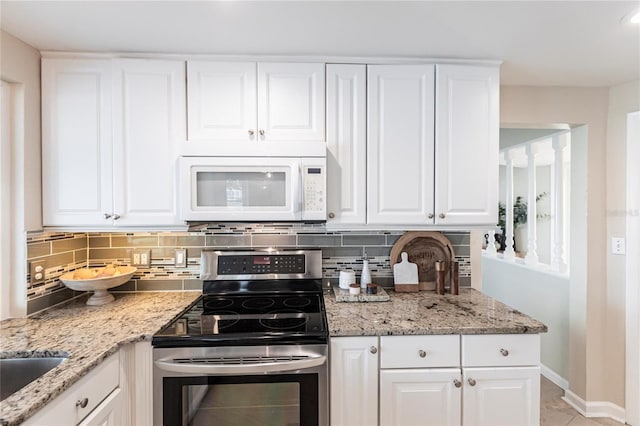 kitchen featuring electric stove, sink, white cabinetry, light stone countertops, and decorative backsplash