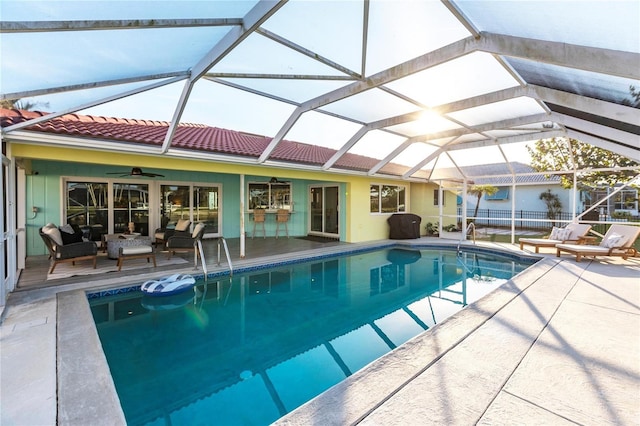 view of swimming pool with ceiling fan, outdoor lounge area, a patio area, and glass enclosure