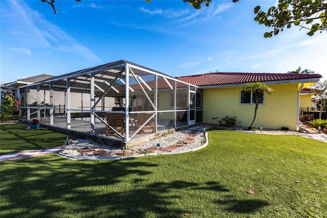 rear view of property featuring a yard, a patio, and glass enclosure