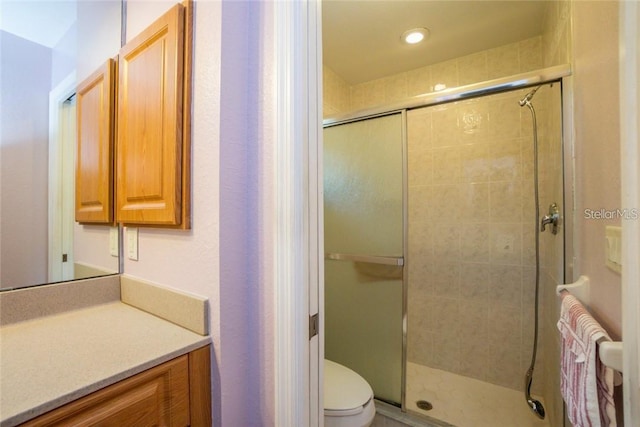 bathroom with vanity, toilet, and a shower with door