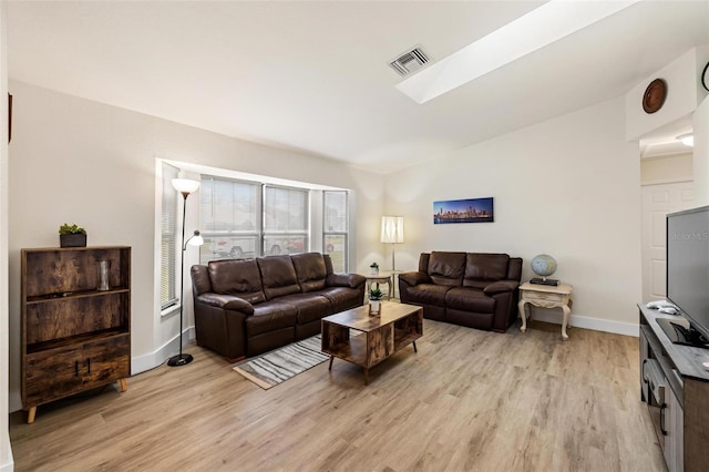 living room with lofted ceiling with skylight and light hardwood / wood-style flooring