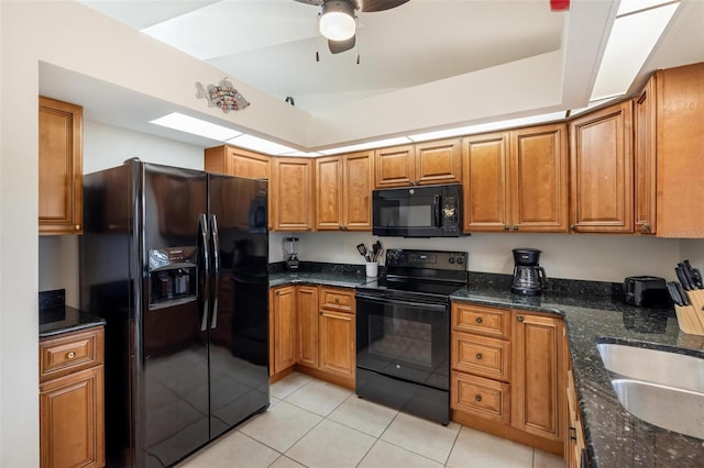 kitchen with light tile patterned flooring, sink, ceiling fan, dark stone counters, and black appliances