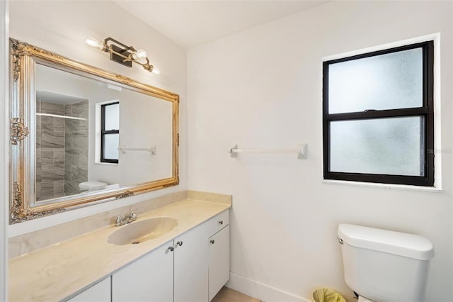 bathroom with vanity, toilet, and tiled shower