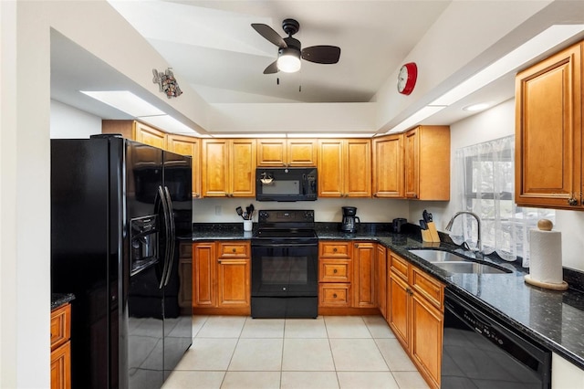 kitchen with sink, dark stone counters, light tile patterned floors, ceiling fan, and black appliances