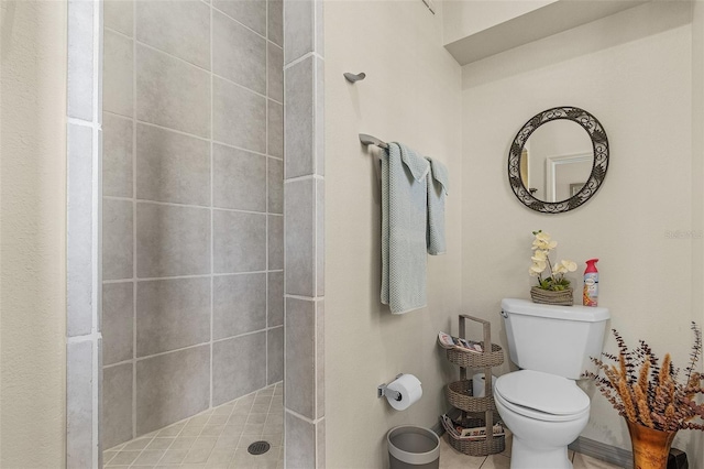 bathroom with a tile shower and toilet