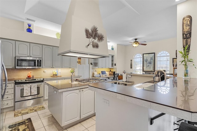 kitchen featuring light tile patterned flooring, appliances with stainless steel finishes, a breakfast bar area, backsplash, and a center island