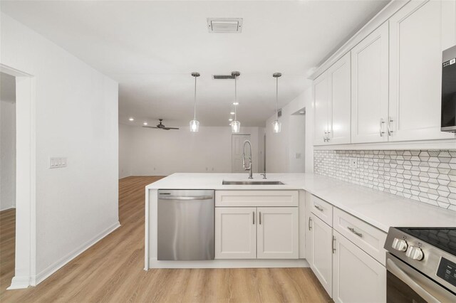 kitchen with appliances with stainless steel finishes, kitchen peninsula, sink, and hanging light fixtures