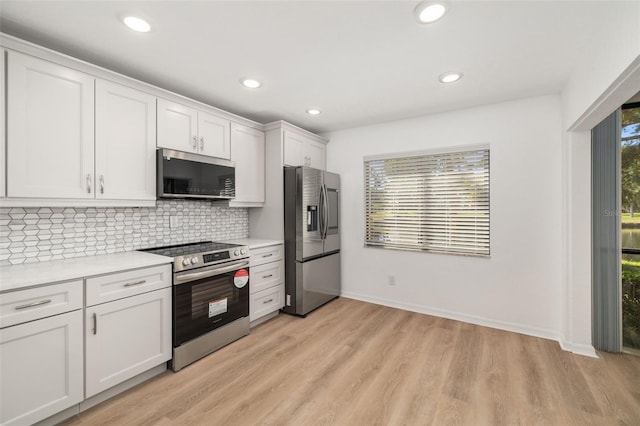 kitchen with white cabinetry, appliances with stainless steel finishes, backsplash, and light hardwood / wood-style floors