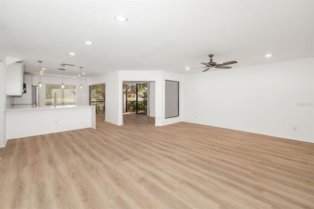 unfurnished living room with ceiling fan and light wood-type flooring