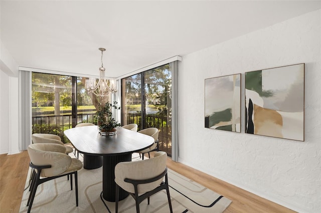 dining space featuring a wall of windows, a chandelier, and light wood-type flooring