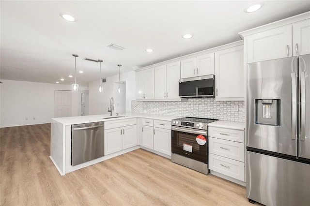 kitchen with appliances with stainless steel finishes, pendant lighting, white cabinets, kitchen peninsula, and light wood-type flooring