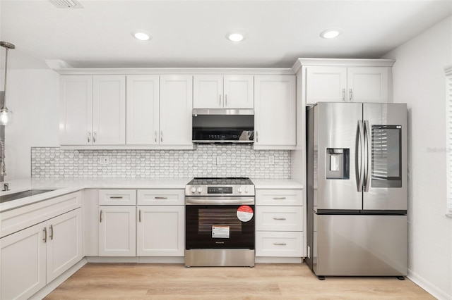 kitchen with light hardwood / wood-style flooring, appliances with stainless steel finishes, white cabinetry, hanging light fixtures, and tasteful backsplash