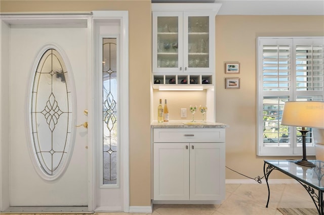 interior space with white cabinetry, light stone countertops, and light tile patterned floors