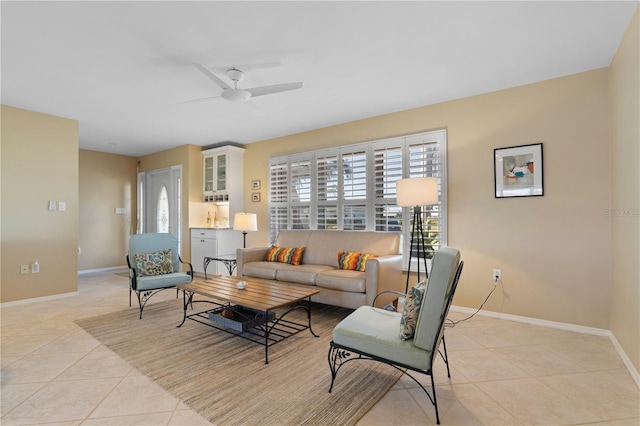 living area with light tile patterned flooring, ceiling fan, and baseboards