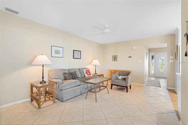 living area featuring light tile patterned floors, ceiling fan, visible vents, and baseboards