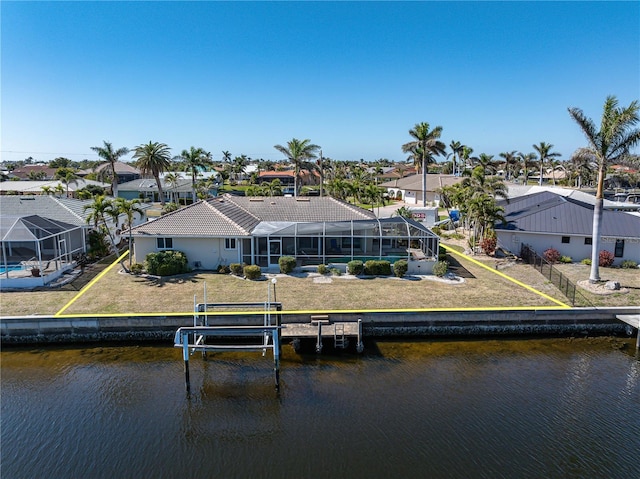 back of house with a water view, a lanai, and a lawn