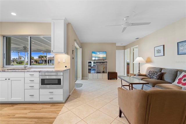 living area with light tile patterned flooring, ceiling fan, and visible vents