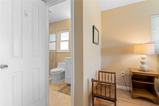 full bathroom featuring toilet, baseboards, and tiled shower