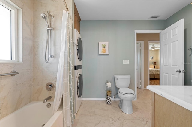 ensuite bathroom featuring baseboards, toilet, ensuite bath, stacked washer / drying machine, and shower / tub combo with curtain