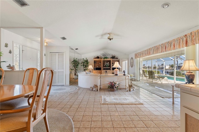 dining room with light tile patterned flooring, ceiling fan, vaulted ceiling, and a textured ceiling