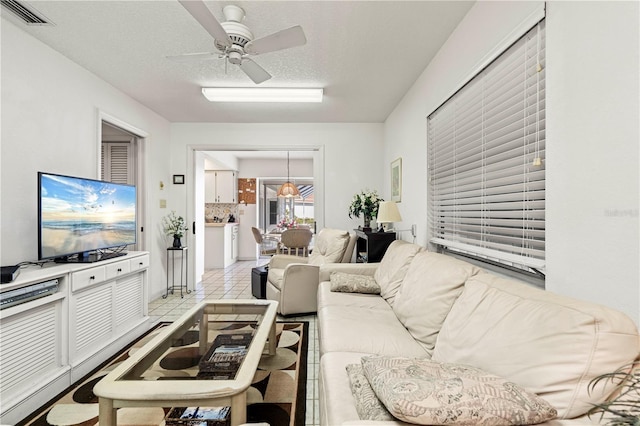 tiled living room featuring ceiling fan and a textured ceiling