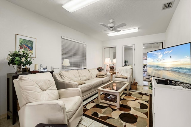 living room with light tile patterned flooring, a textured ceiling, and ceiling fan