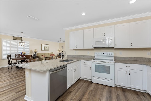 kitchen with a peninsula, white appliances, a sink, and white cabinets